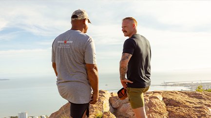 Two men taking a break from a hike, pausing to talk together. 