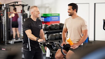 A Mates4Mates physiotherapist instructing a client on an indoor bike. 