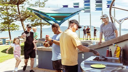 Group of people at an outdoor BBQ in the park on a sunny day. 