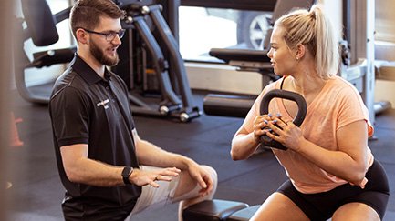 An exercise physiologist works with a woman on a workout routine.