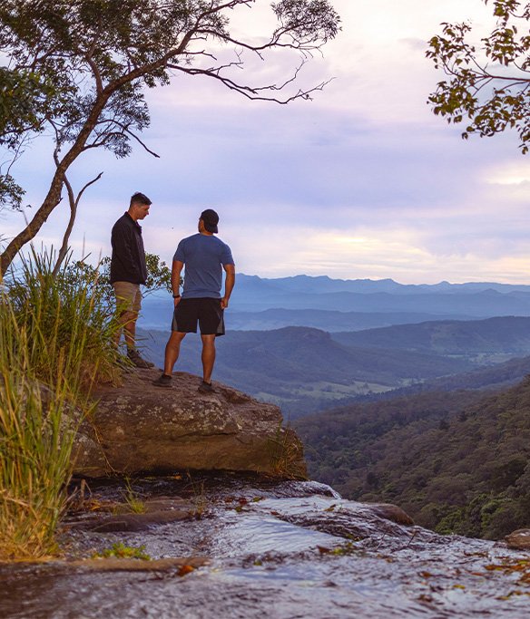 Two people standing at the edge of a waterfall having a meaningful conversation. 