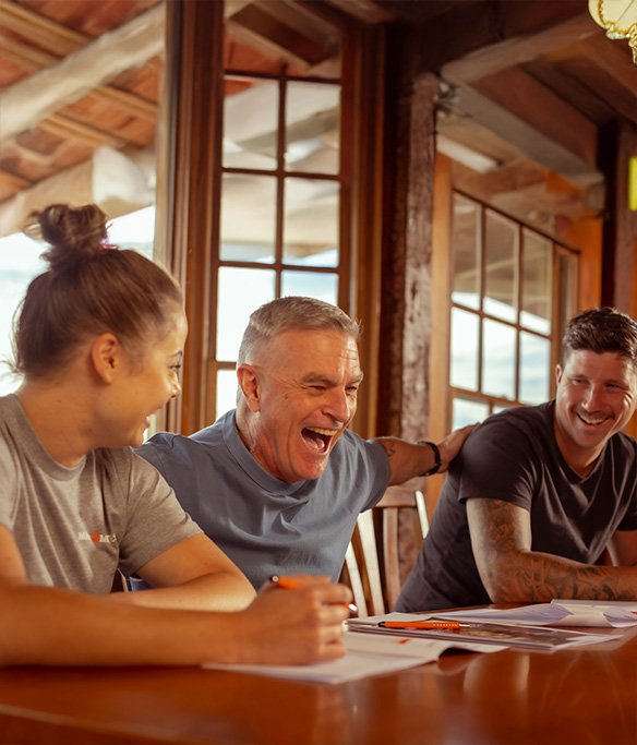 Group sitting at a table indoors laughing together.